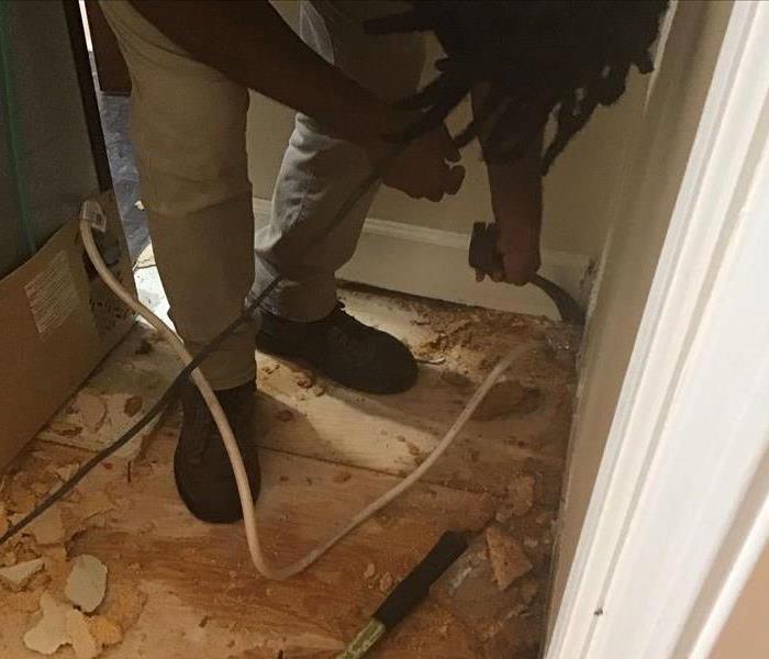 A SERVPRO® Technician removes damaged flooring, revealing the subfloor and saturated subfloor. 