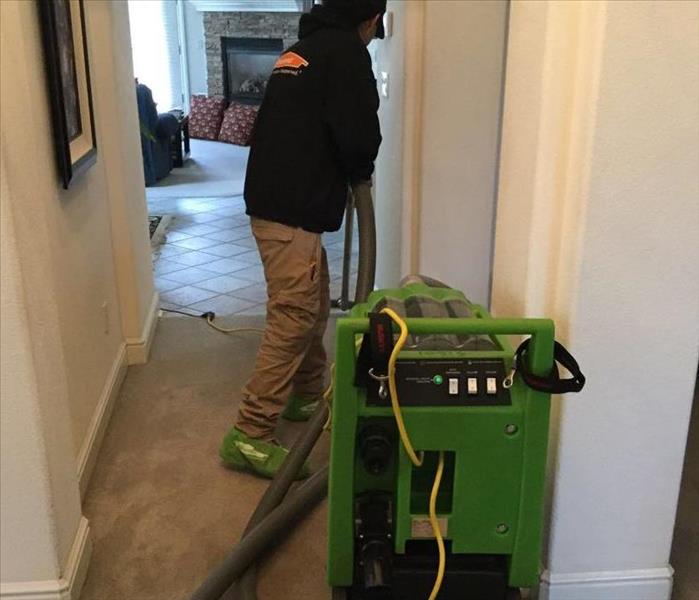 SERVPRO team member extracting water from a hallway carpet